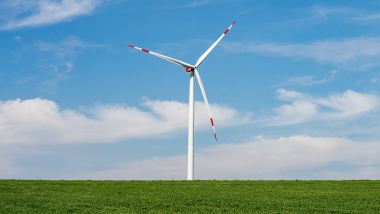 Ein Windrad steht in der Landschaft.